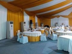 a banquet hall with tables and chairs covered in white tablecloths, yellow drapes and gold trim