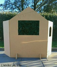 a cardboard house with a mirror on the front and side wall, sitting in a driveway