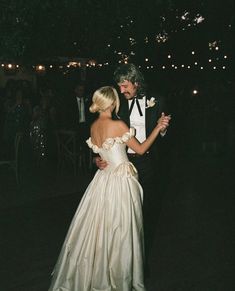 a man in a tuxedo and a woman in a wedding dress dance together