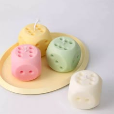 three different colored dices on a plate with one candle in the middle and two smaller ones