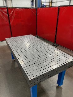 a metal table sitting inside of a garage next to red partitions on the wall