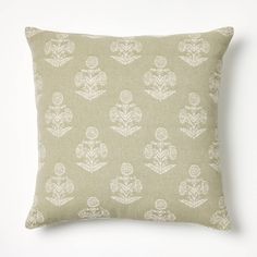 a green pillow with white flowers and leaves on the front, against a white background