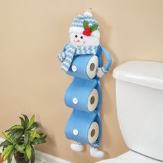 a toilet paper roll snowman hanging on the wall next to a potted plant