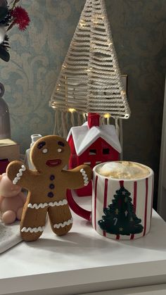 there is a gingerbread man next to a cup of coffee and a christmas tree