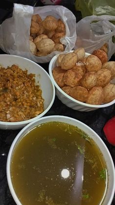 three bowls filled with different types of food on top of a black table next to plastic bags