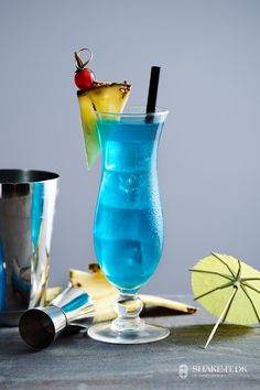 a blue drink in a tall glass with a pineapple garnish on top