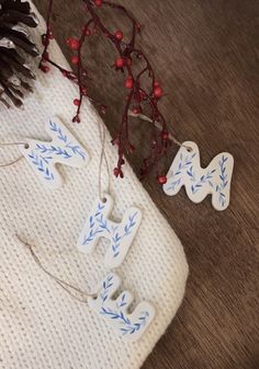 two wooden letters are hanging from a string on the floor next to pine cones and berries