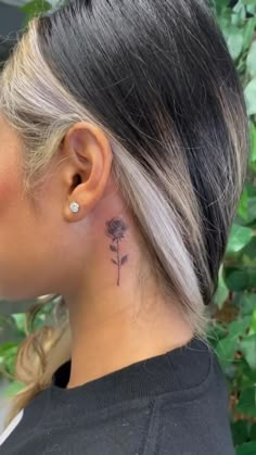 a woman with a small flower tattoo on her left ear