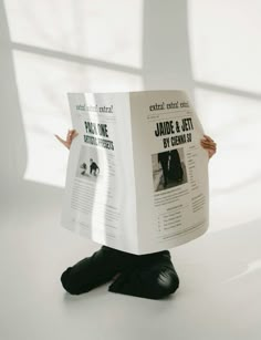 a person sitting on the ground holding up a book with their hands and legs in front of them