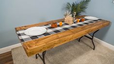 a wooden table with plates and cups on it in front of a blue painted wall