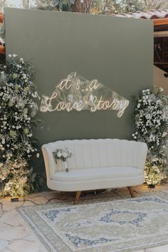 a white couch sitting in front of a sign that says it's a love story