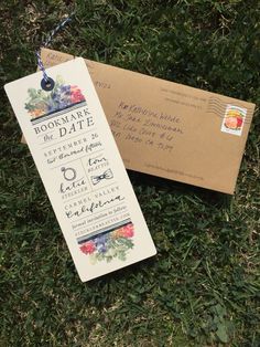 a wedding save the date card and envelope laying on some grass next to an envelope