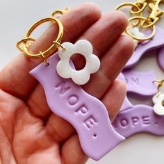 a hand holding two purple and white keychains with the word hope written on them