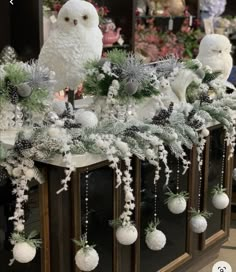 two white owls sitting on top of a christmas mantle decorated with silver and white ornaments