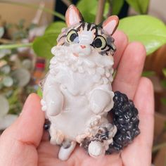 a hand holding a small cat figurine in it's palm