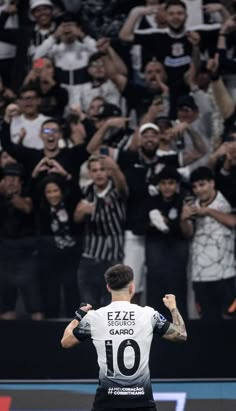 a man standing on top of a field holding a soccer ball in front of a crowd