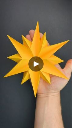 a hand holding an origami sunflower on a black background with the video below it