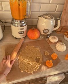 a person is making pumpkin cookies on a counter with an orange juice in the blender