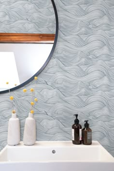 a white sink sitting under a round mirror