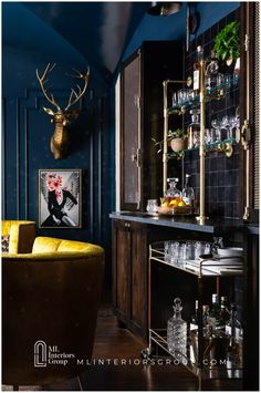 a room with blue walls and furniture in the center is filled with liquor bottles, glasses, an antelope head hanging on the wall