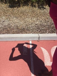 the shadow of a person standing in front of a parking lot with a stop sign