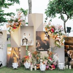 a bunch of pictures and flowers are on display in front of a wall with photos