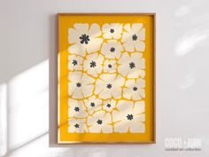 a yellow and white flowered art piece hanging on a wall