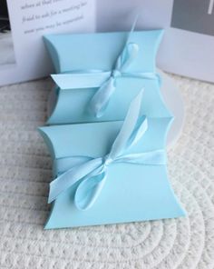 three blue boxes with white bows on them are sitting on a table next to a card