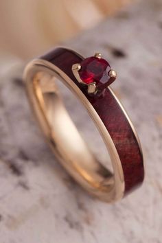 a gold ring with a red stone in the center on top of a marble surface