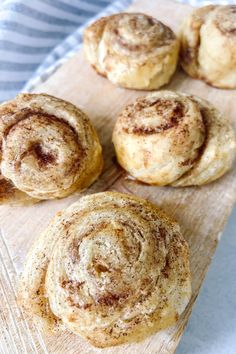 cinnamon rolls sitting on top of a wooden cutting board