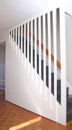 an empty room with wooden floors and white railings on the wall, next to a set of stairs