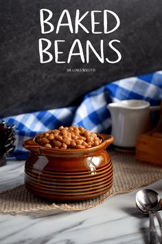 a wooden bowl filled with baked beans on top of a table next to silverware