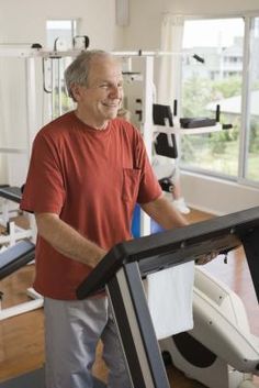 an older man walking on a treadmill in a gym with other exercise equipment behind him