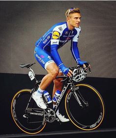 a man riding on the back of a bike in front of a wall with an advertisement behind him