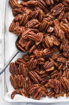 a tray filled with pecans next to a spoon