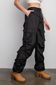 Experience effortless comfort and functionality with our Parachute Cargo Pants. Featuring a zipper with button closure, elastic band for the perfect fit, drawstrings for capri length adjustments, and convenient multiple pockets. Crafted from lightweight, windbreaker fabric for lightweight all-day wear.- Drawstring- Back Pockets- Side PocketsModel is 5'9" and wearing size Small. True to size.Fabric Content: 100% Nylon Utility Nylon Bottoms For Outdoor, Nylon Techwear Bottoms With Functional Pockets, Black Functional Nylon Bottoms, Functional Black Nylon Bottoms, Nylon Long Pants With Functional Drawstring, Functional Parachute Pants For Outdoor Activities, Black Utility Parachute Pants, Nylon Hiking Bottoms With Cargo Pockets, Nylon Techwear Pants With Functional Drawstring