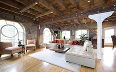 a living room filled with lots of furniture next to two large arched windows and wooden floors