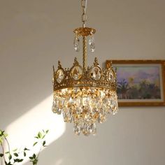 a gold chandelier hanging from the ceiling in a room with paintings on the wall