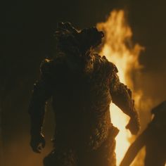 a godzilla standing in front of a fire