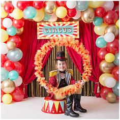 a child is sitting on a circus float surrounded by balloons and streamers with a circus sign in the background