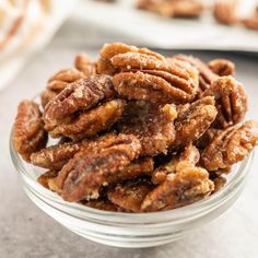 a glass bowl filled with pecans on top of a table