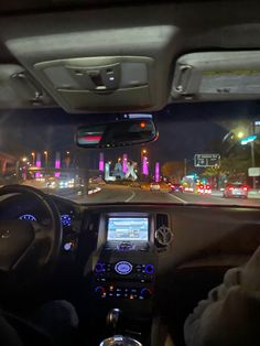 the interior of a car with dashboard lights on at night and traffic in the background