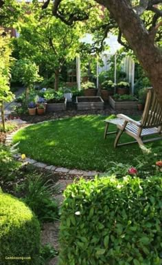 a wooden bench sitting in the middle of a lush green yard next to a tree