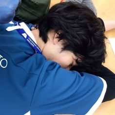 a young man sleeping on top of a wooden table