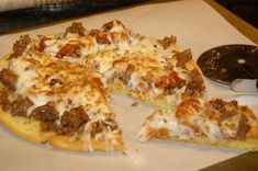 a pizza sitting on top of a cutting board next to a knife and spatula