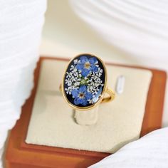 a ring with blue and white flowers on it sitting on top of a wooden box