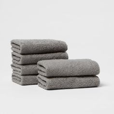 six towels stacked on top of each other in front of a white background with one folded up