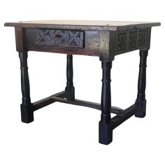 an old wooden table with black legs and carvings on the top, against a white background