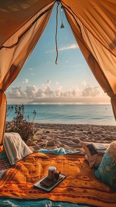 a bed sitting under a tent on top of a sandy beach next to the ocean