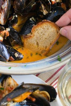 a bowl filled with mussels next to bread on top of a white plate